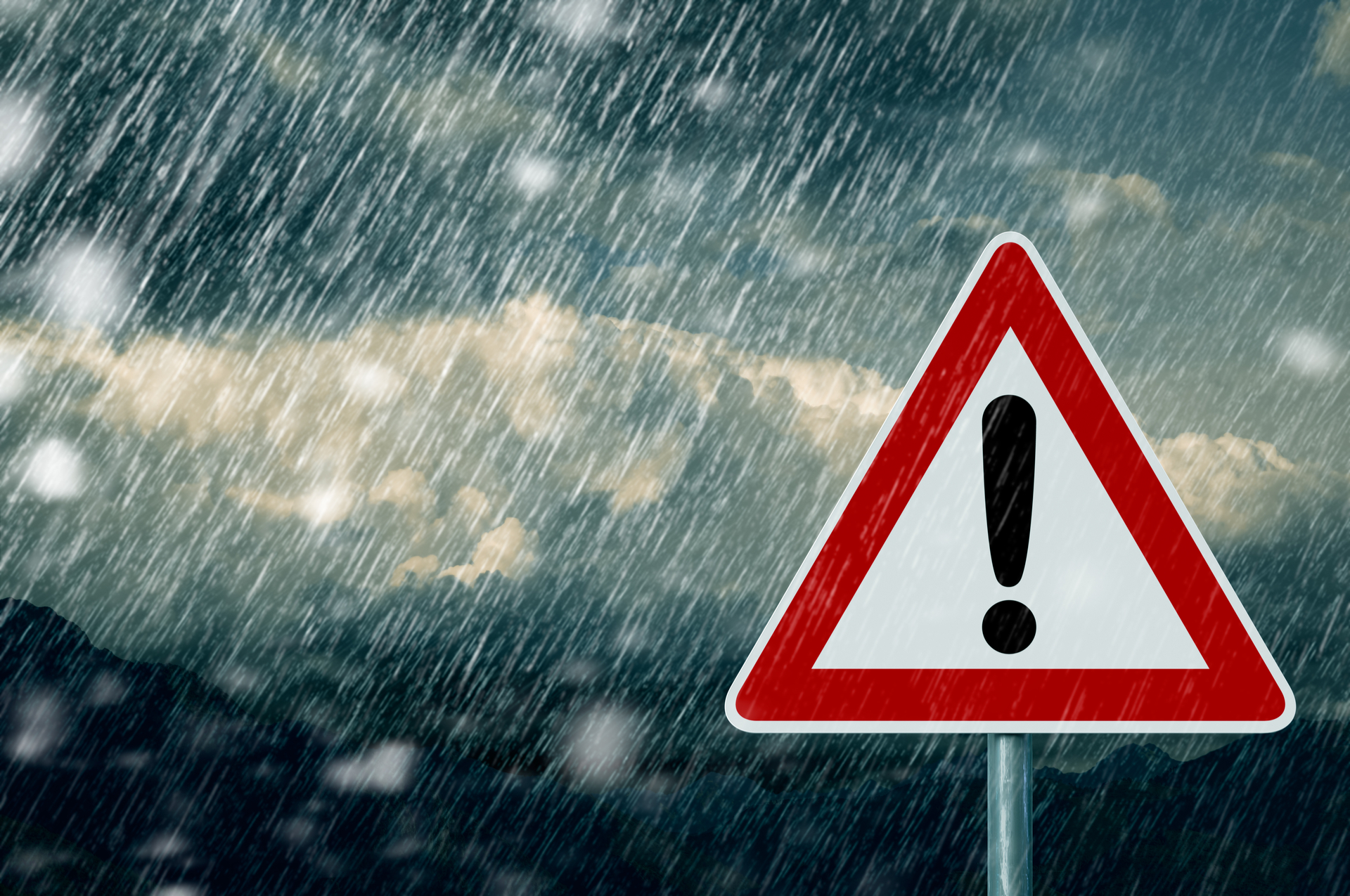 A red warning sign with torrential rain and grey clouds in the background