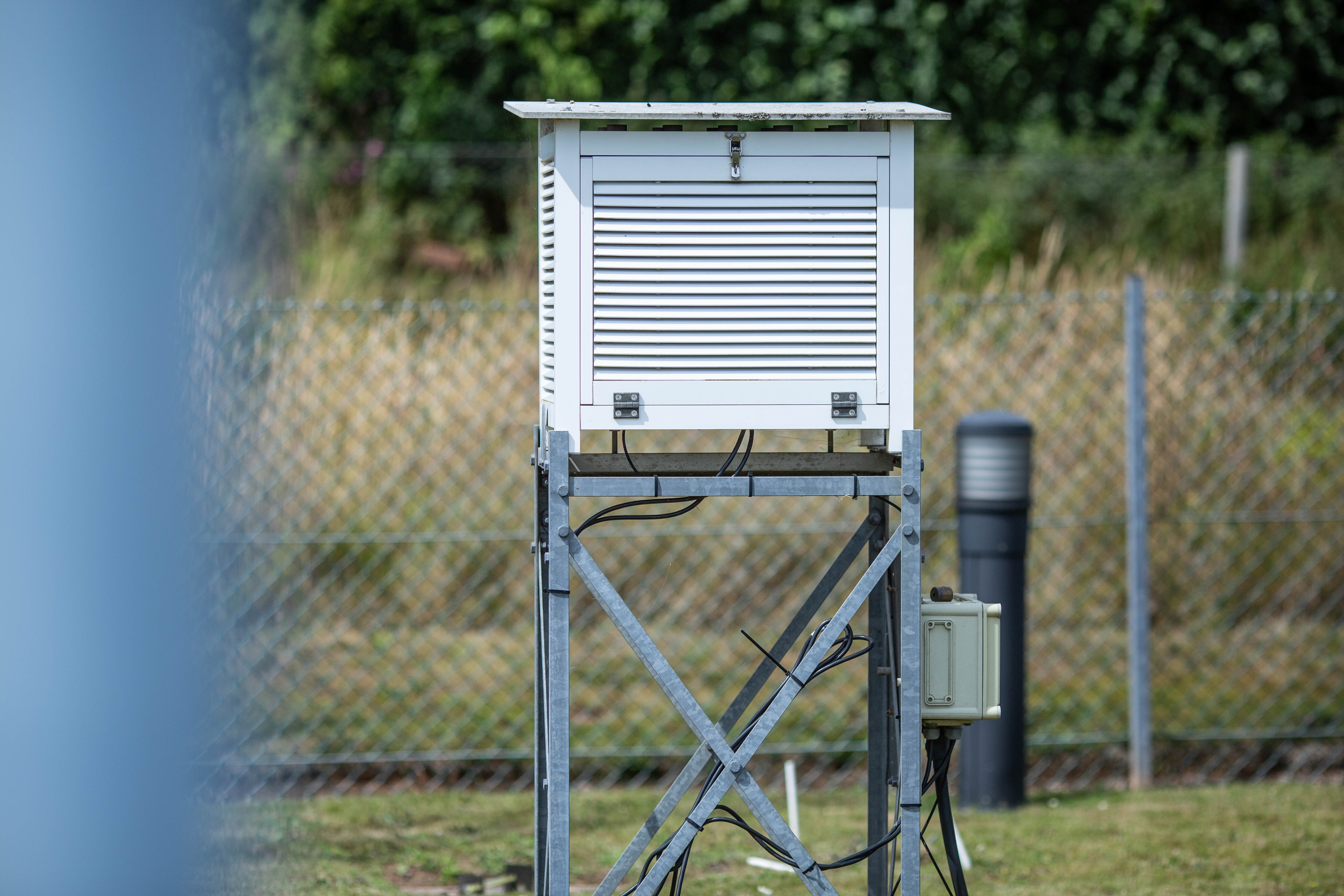 A square weather station on a stand in a field